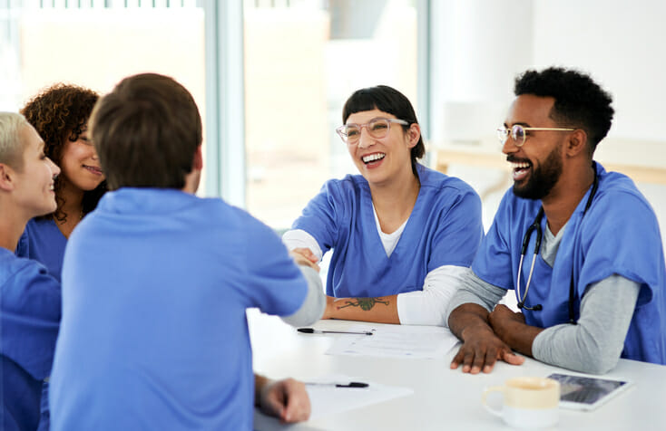 A group of people in scrubs meet around a table